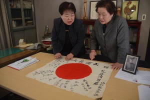 阿部博子山形県遺族会副会長から日章旗を受け取った荒井菊子さん（右）