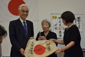 真鍋賢二会長（左端）より日章旗を受け取り喜びを語る大西さん（中央）